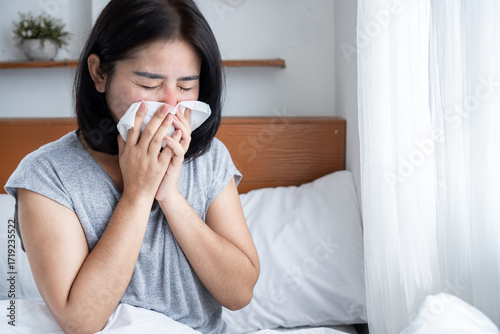 Asian woman coughing, sneezing, and suffering from a runny nose caused by cold, flu, or seasonal allergies. Symptoms triggered by dust, PM2.5 air pollution, and poor air quality