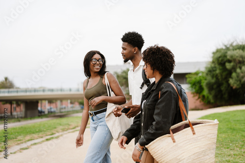 A group of three friends are walking and talking while one of them smiles