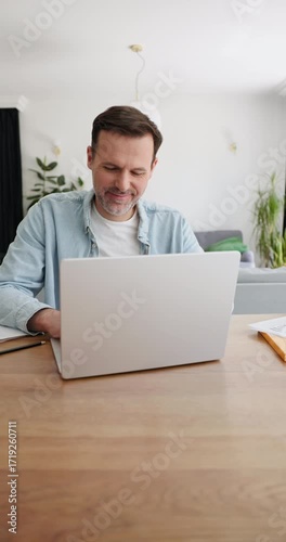 Vertical video of man opening laptop and using at home