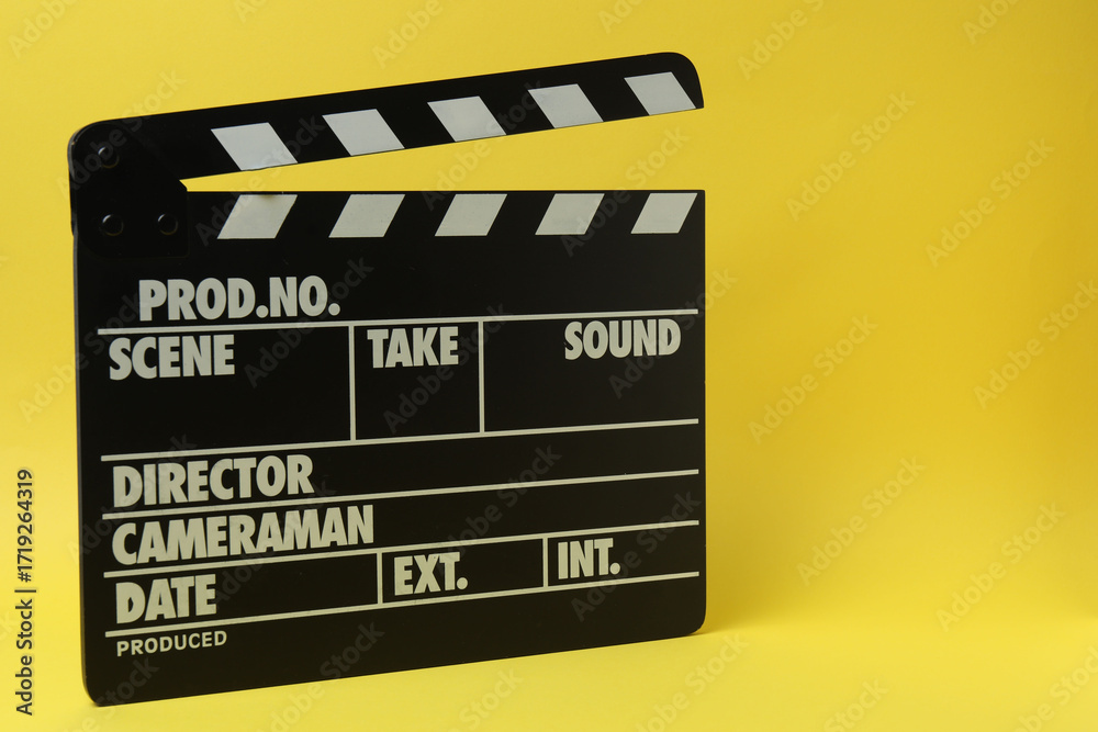 Naklejka premium Cinema clapper and reel on a yellow background