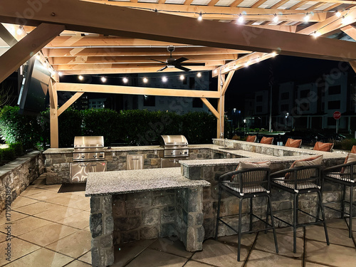 Outdoor stone bar and grill area at night with string lights and seating
