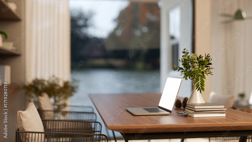 Fototapeta premium White screen laptop with book and glasses aside vase on wooden table with metal chair in living room