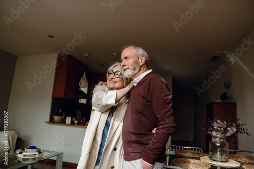 A man and a woman are hugging and looking ahead while she smiles