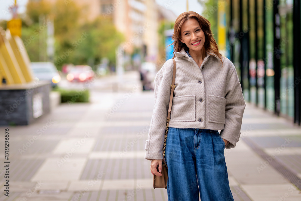 Fototapeta premium A stylish middle-aged woman walking on an autumn day on a city street