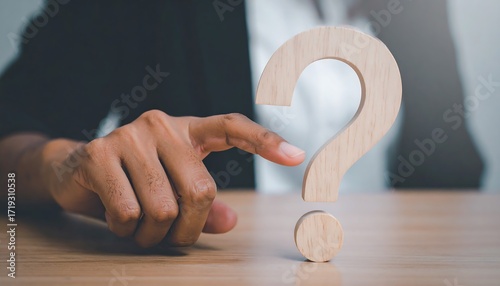 Wooden question mark icon touched by businesswoman hand symbol of curiosity and guidance