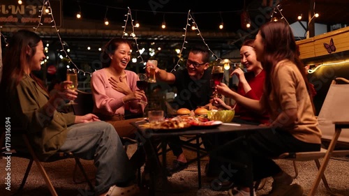 Happy Friends Celebrating Together at Night, Asian Group of Friends Having Fun and Toasting Drinks Outdoors, Enjoying a Celebration Concept.
