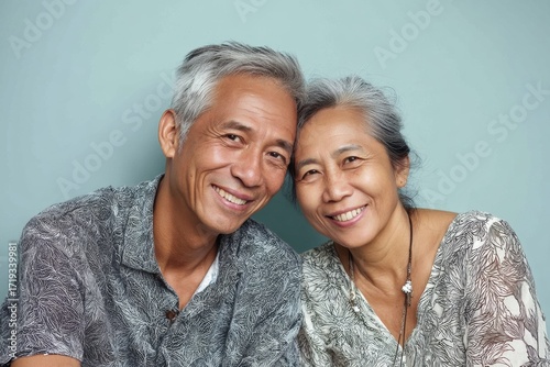 Portrait of a cheerful asian couple in their 60s sporting a breathable hiking shirt while standing against pastel or soft colors background