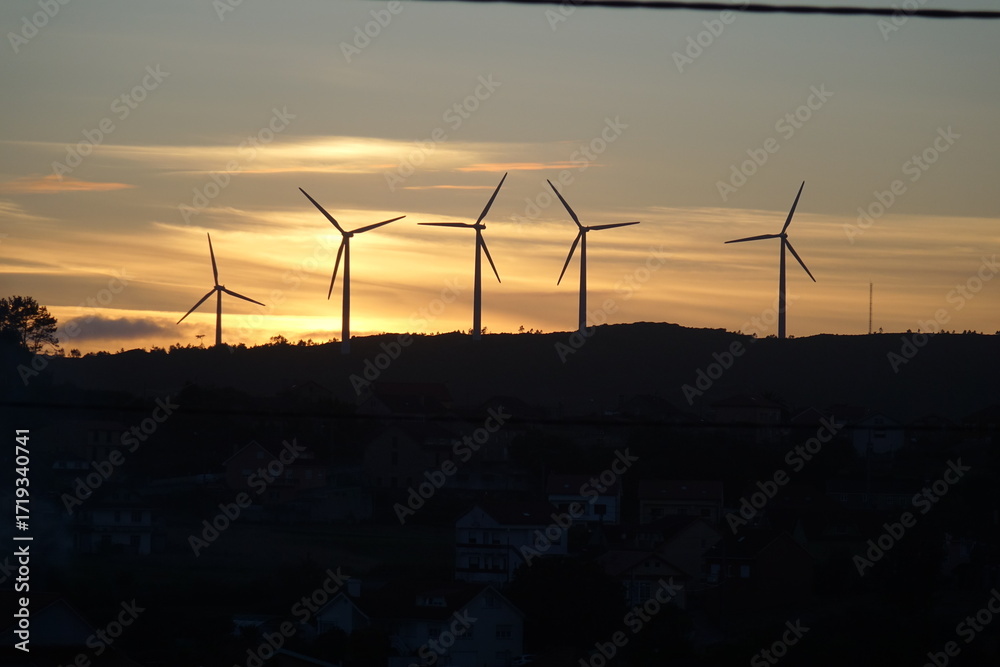 Obraz premium Tramonto mozzafiato su un campo eolico, simbolo di energia pulita e futuro sostenibile. Silhouette di turbine a vento contro cieli infuocati