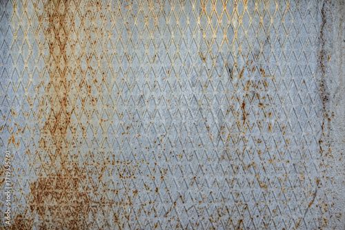 Texture of a ribbed, rusty metal surface with a diamond pattern
