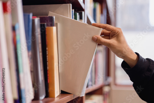 hand taking binder from bookshelf in office library. Concept of business organization, document management, archive, education, and knowledge storage.