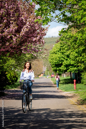 Wallpaper Mural Confident middle-aged woman riding bicycle on the road in spring time Torontodigital.ca