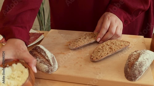 Female hands spreading soft ricotta cheese on bread during sandwich cooking close up