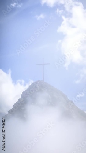 Summit cross atop a peak, shrouded in mist