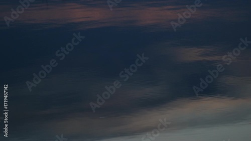 Still water reflecting clouds with subtle waves. Relaxing abstract nature background concept. Calm liquid surface at sunset.