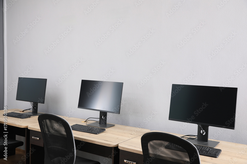 Fototapeta premium Open office interior. Modern workplaces with computers near light grey wall