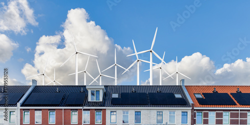 Row of new modern Dutch family houses in front of a field with large wind turbines