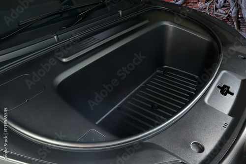 an empty frunk or front trunk , storage compartment in a modern electric car or super car showing modern black interior design and practical space for luggage or everyday items frunk is storage space