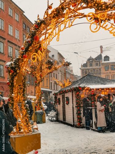 Christmas market. Festive atmosphere with Christmas tree, holiday lights, carousel, ferris wheel and crowds of people enjoying the winter event. European holiday
