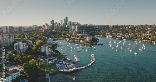 Australia, Sydney: Sydney's modern city skyline above Rushcutters Bay, featuring boats sailing in marina and sunlit residential buildings skyscrapers. Aerial view drone flight footage panorama