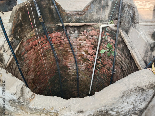 Traditional brick well interior with multiple pipes for submersible water pumps used in Indian villages for agricultural irrigation