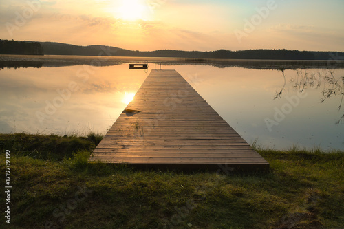Romantic jetty on the lake at sunset with calm water