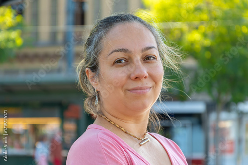 Street portrait of a dark-haired woman aged 40-45 years on the background of a city street.