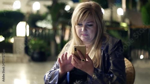 Woman female listens to music using a smartphone in the evening with amazing bokeh.