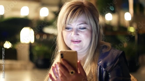 Woman female listens to music using a smartphone in the evening with amazing bokeh 