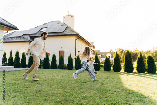Happy family playing and running together in the backyard of their modern house