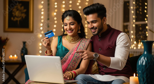 young indian couple holding credit card and using laptop together on diwali festival