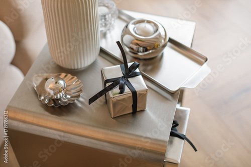 Overhead view of a wrapped Christmas gift on a coffee tablet assorted silver accessories and candles