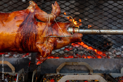 Quadro su tela Vue d’un cochon entier cuit à la broche lors d’une préparation traditionnelle, illustrant une cuisson lente en extérieur avec une présentation conviviale