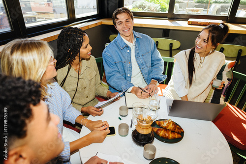 Startup team brainstorming in a relaxed coffee shop setting over coffee and pastries