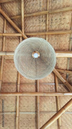 A decorative lamp crafted from woven rattan, casting warm light through natural patterns and showcasing elegant handmade craftsmanship.