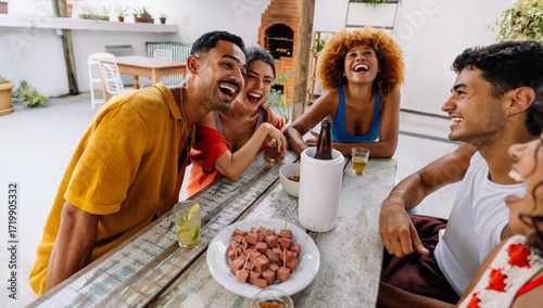 Group of five friends laughing while sharing petiscos on a patio
