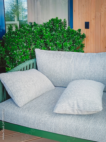 A comfortable chair with cushions and decorative plants on the terrace. A place to relax. Vertical photo.