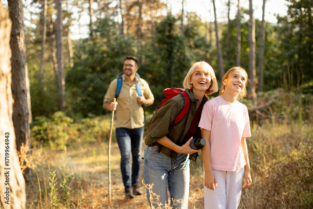 Fototapeta premium Family enjoys nature hike in the forest during sunny afternoon with smiles and laughter