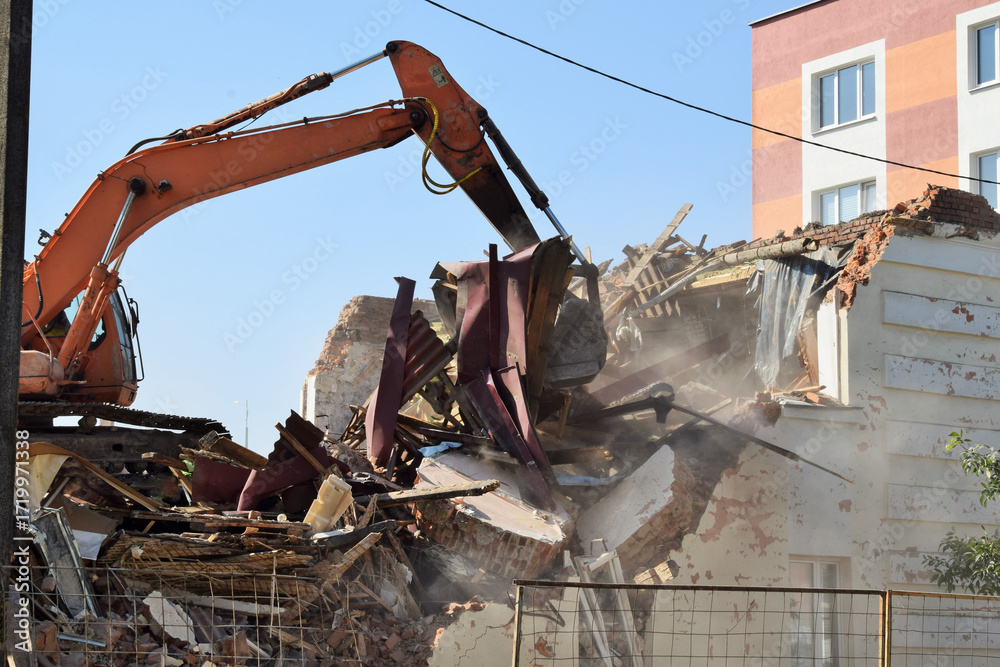 Fototapeta premium A modern excavator removes the remains of a destroyed residential building.