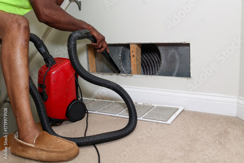 a portrait of a black man cleaning a air duct