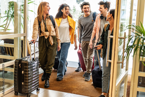 Young group of tourists with suitcases arriving at youth hostel guest house - Happy friends enjoying summer vacation together - Millenial people doing check-in at hotel lobby - Summertime holidays