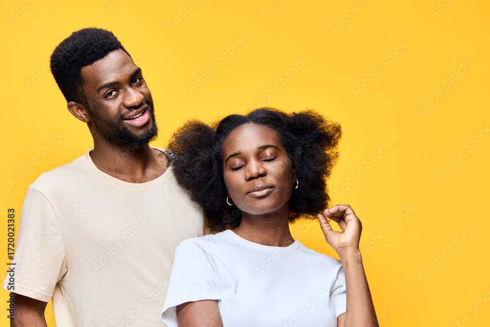Fototapeta premium Happy young couple with natural hairstyles against a bright yellow background, representing love and positivity through vibrant colors and joyful expressions