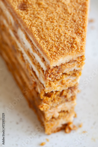 top view of  Slice of delicious layered caramel honey cake served on ceramic plate