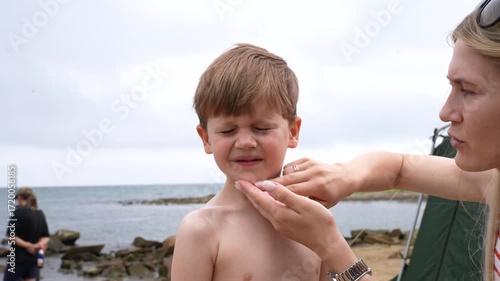 Mom rubs sunscreen on her child's face