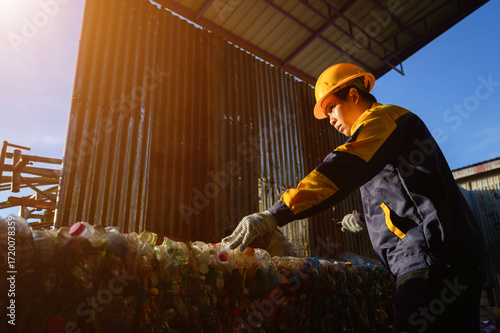 Asian worker in helmet recycling plastic bottles at factory, recycling industry, recycling service, environment protection and recycling process.