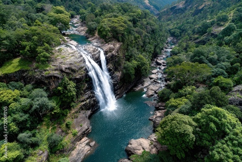 Aerial View of Majestic Waterfall Cascading into a Lush Green Valley