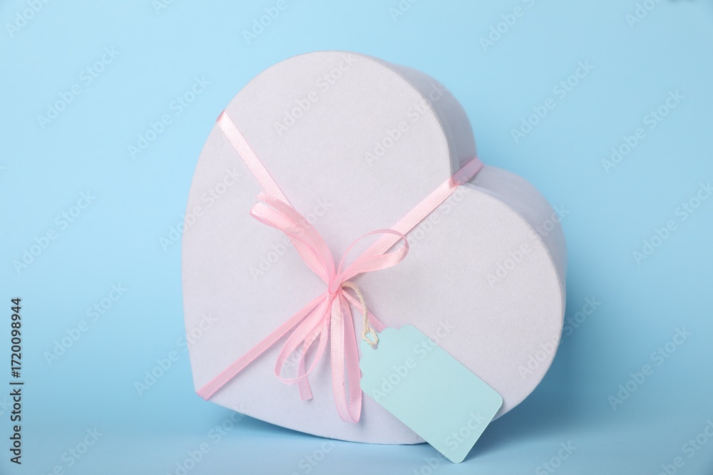 Fototapeta premium Gift box with blank tag on light blue background