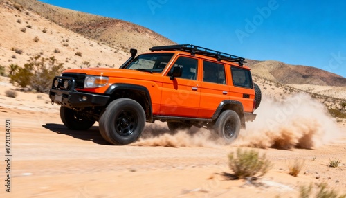 Orange off-road vehicle driving on a sandy mountain road in summer daylight.