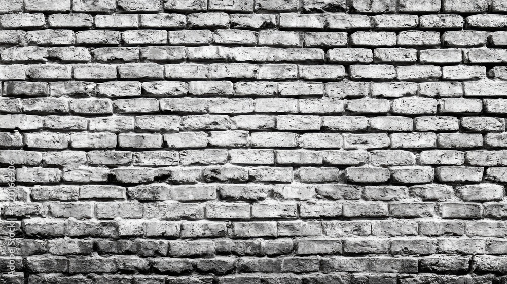 Fototapeta premium A close-up view of a weathered brick wall reveals the unique texture and character of the bricks, highlighting signs of age and time. The monochrome effect enhances its rustic appeal.