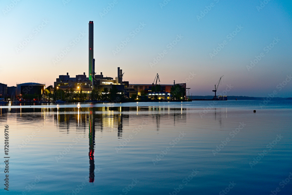 Obraz premium Flensburg metal works at dusk with green lit chimney