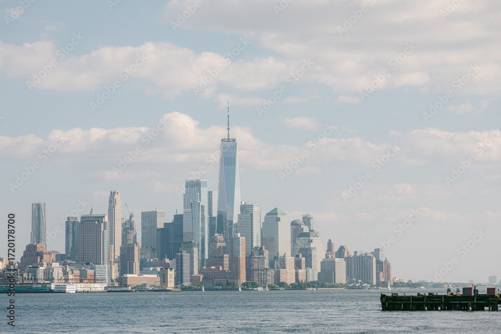 Obraz premium Skyscrapers rise over the water in New York City with a calm sky and clear day